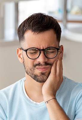 Man with black glasses experiencing toothache
